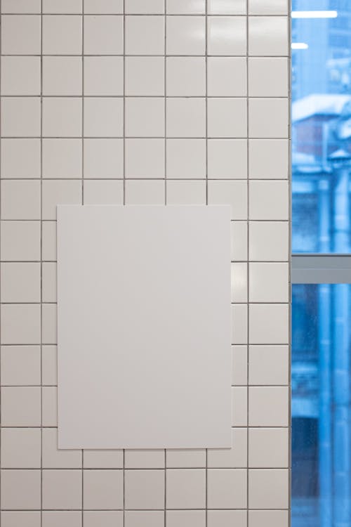 White mock up paper with copy space hanging on wall with tiles near window in light room in modern studio