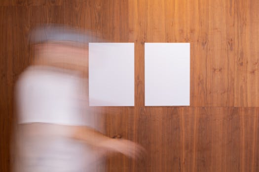 Motion blurred person walking past two blank posters on a wooden wall. Ideal for mockups or design presentations.