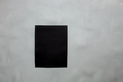 Rectangular creative black mock up poster with copy space hanging on empty gray wall in light room of modern studio