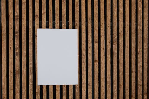 White mock up poster with copy space hanging on decorated wall with creative wooden planks in room of modern studio