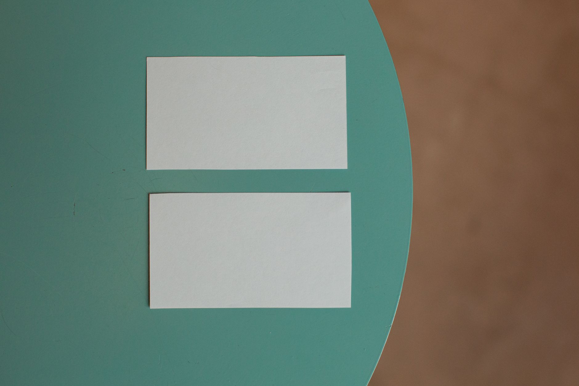 Top view of creative white mock up business cards with copy space placed on round green table in light room