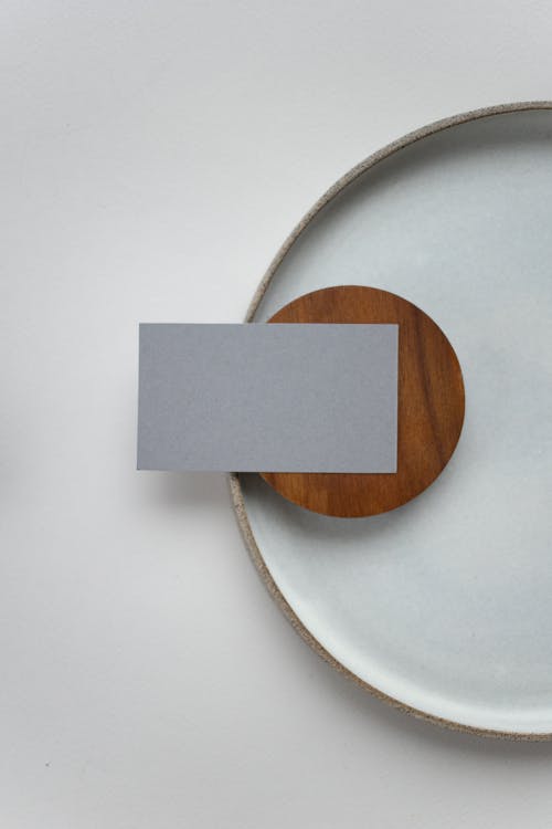 Top view of small gray rectangular mock up name tag placed on round plate on white table in light room