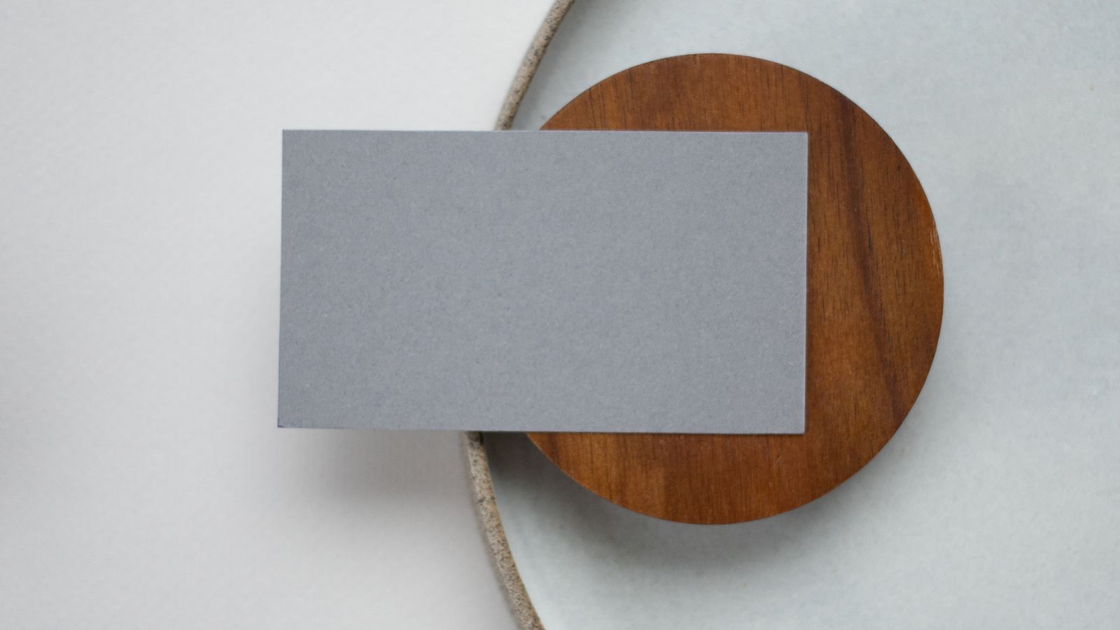 A blank grey place card on a wooden disc and white plate