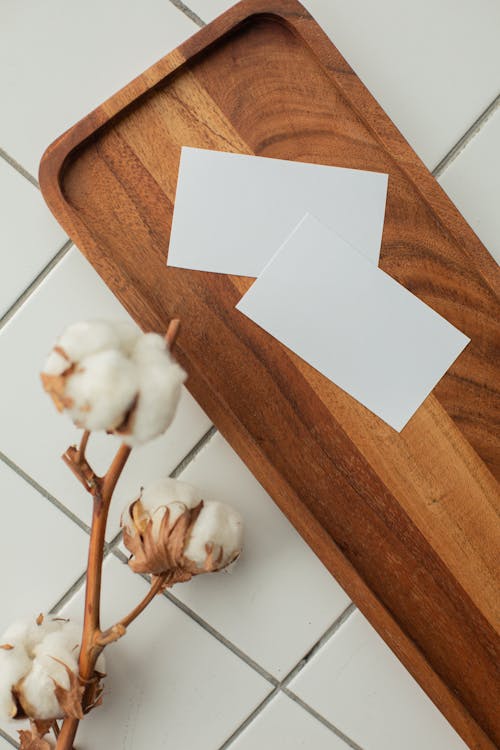 Top view of white mock up business cards with copy space on tray near cotton flowers in light room with tiled floor