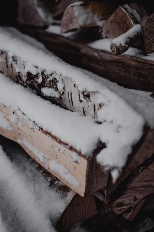 Free A close-up view of firewood covered in snow, depicting a cold winter setting. Stock Photo
