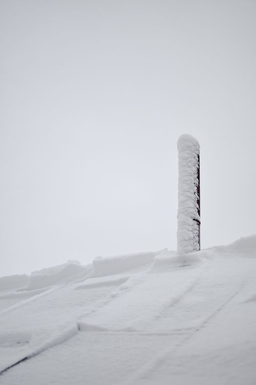 Free A chimney and roof covered in fresh snow against a white winter sky, capturing Estonia's serene winter beauty. Stock Photo