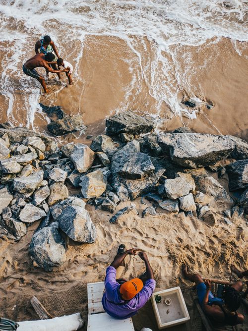 Free A vibrant scene of people enjoying the sandy shore and rocky beach in Kasoa, Ghana. Stock Photo