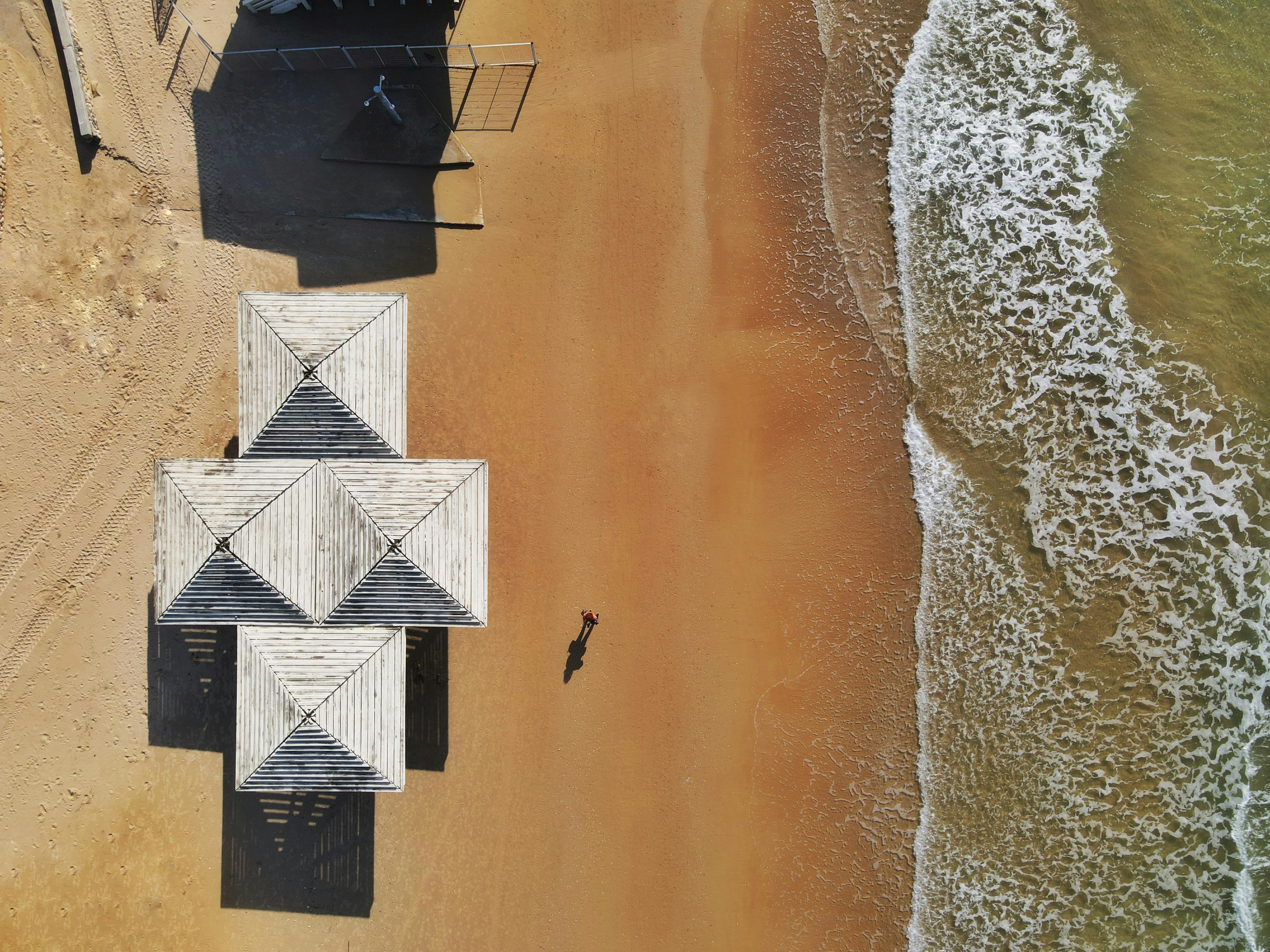 A stunning aerial view of sandy beach and white structures next to waves in Haifa, Israel.
