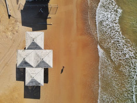 A stunning aerial view of sandy beach and white structures next to waves in Haifa, Israel.