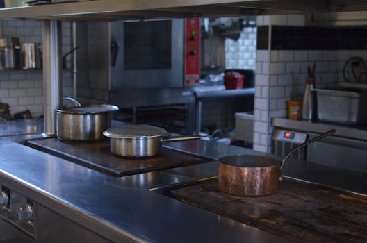 Stainless steel pots on a kitchen counter in a professional restaurant setting.