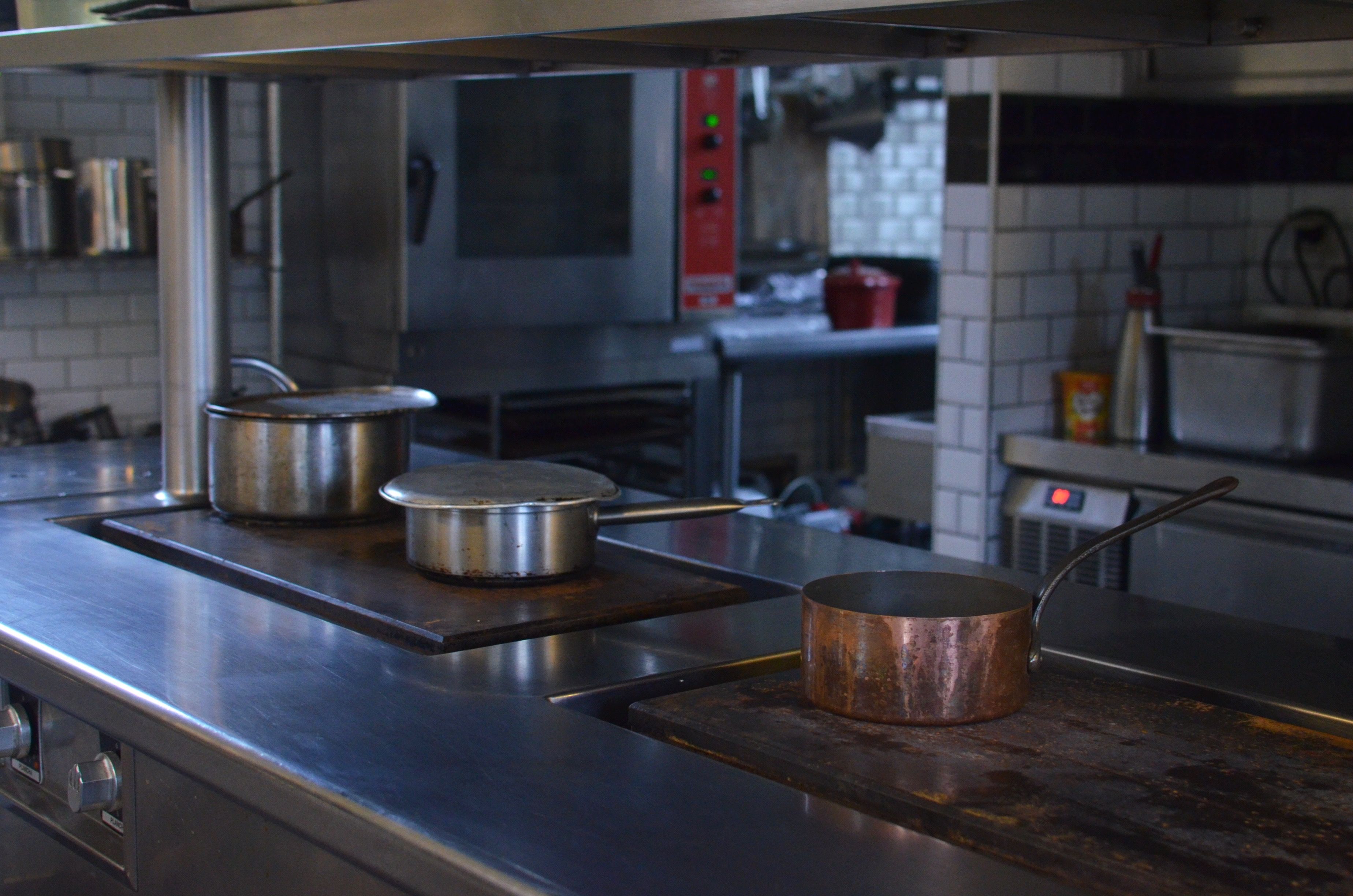 Casseroles en acier inoxydable alignées sur le plan de travail d'une cuisine professionnelle entretenue