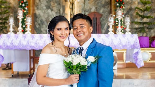 Smiling Asian newlyweds standing in church