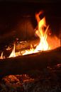 Bright orange blazing flames of fire in aged stone fireplace in dark room