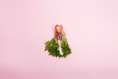Free A visually creative display of lettuce and strawberry on a pastel pink background. Stock Photo