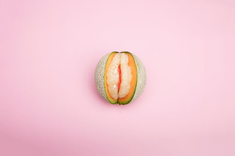 Artistic image of a melon and grapefruit on a pink backdrop, creatively styled.