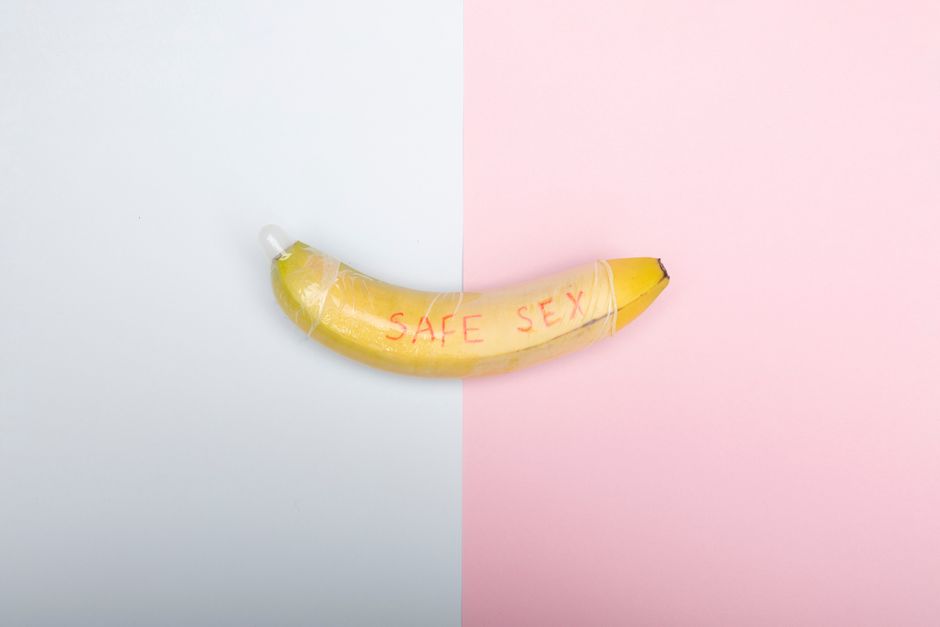 Conceptual image of a banana with condom promoting safe sex education against a pastel backdrop.