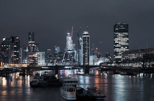 白色和黑色的小船，在夜間城市建築物附近的水面上