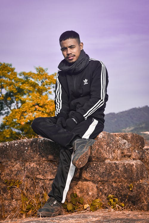 Man in Adidas Sports Wear Sitting on the Rock Free Stock Photo