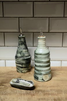 Rustic ceramic bottles and salt holder on wooden counter, ideal for creative kitchen decor.