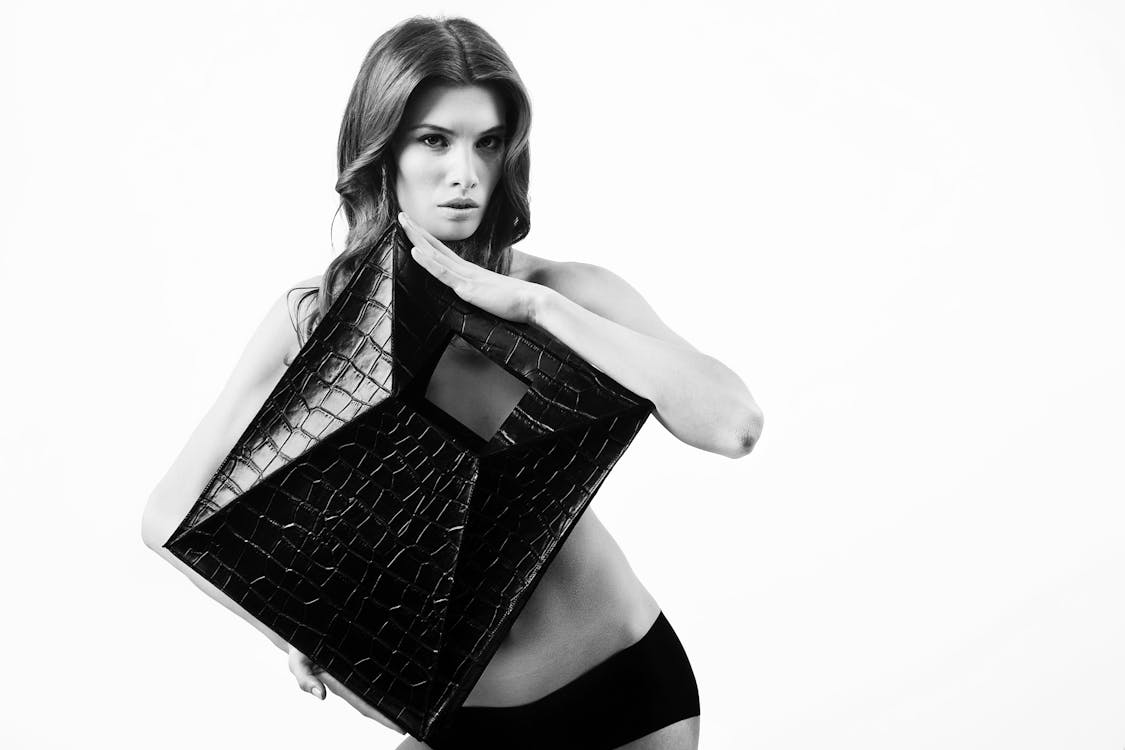 無料 上半身を覆う革の正方形を保持している女性のグレースケール写真 写真素材