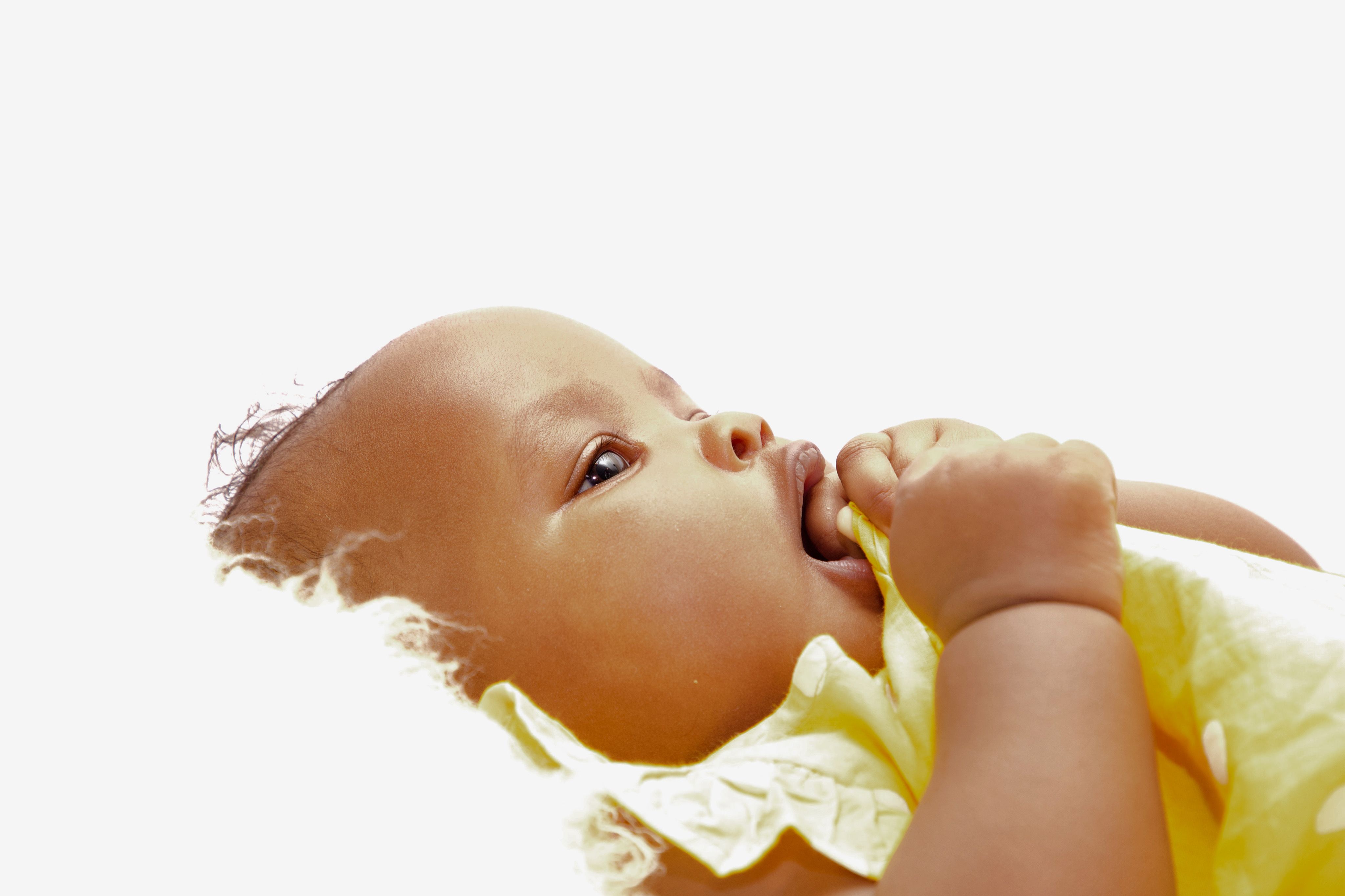 A cute baby lying down on a soft surface, holding a cloth with a serene expression.