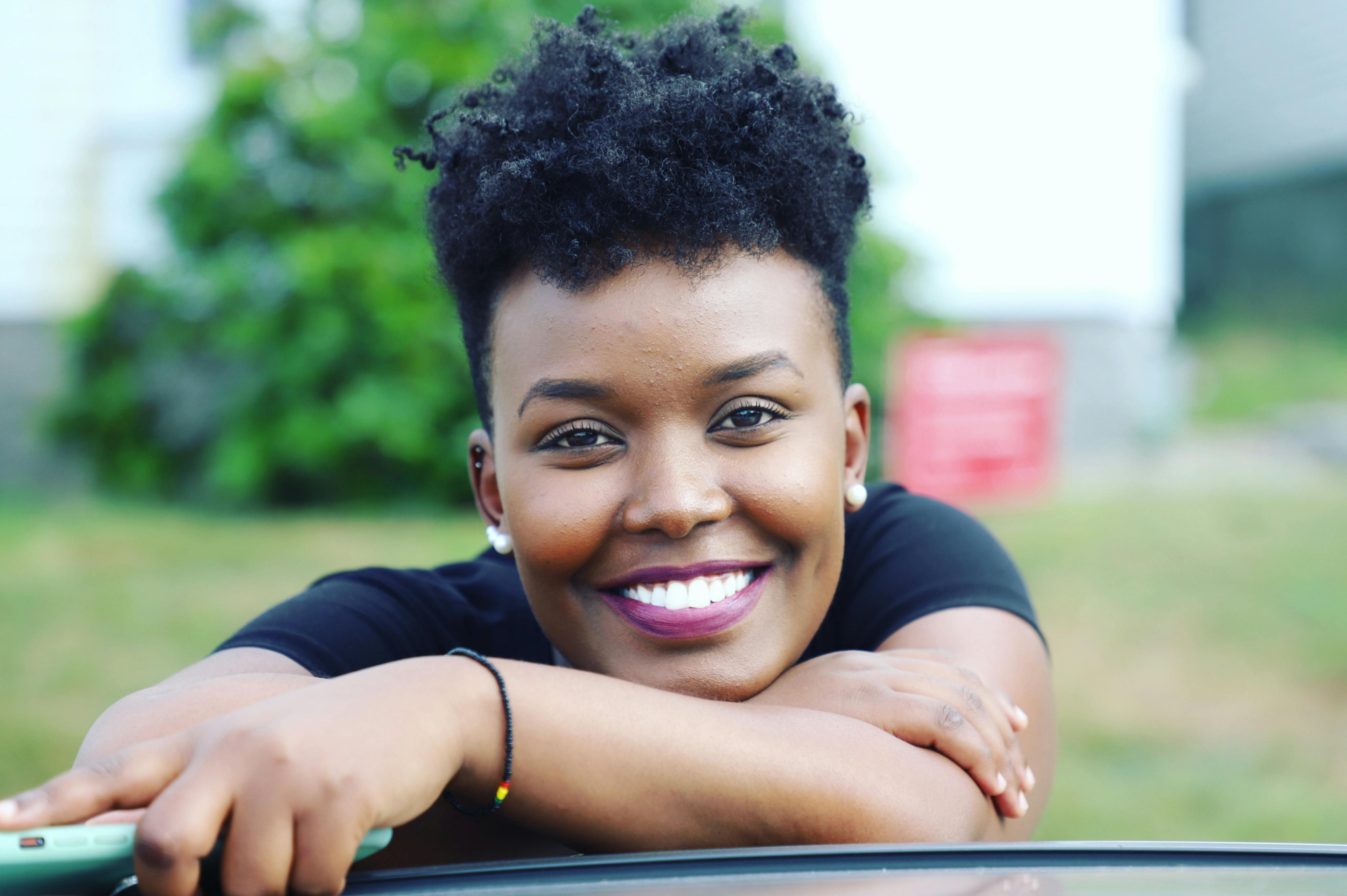 Cheerful young woman with curly black hair smiling outdoors in Lewiston, Maine.