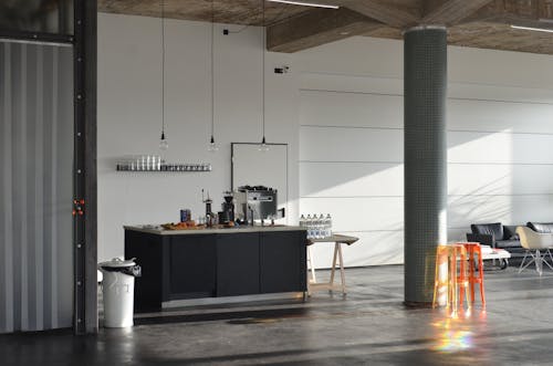 A Black Kitchen Counter Beside a Table with Bottled Water