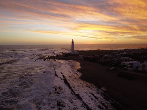 Free A breathtaking aerial view of the La Paloma Lighthouse at sunset, with vibrant skies and ocean waves. Stock Photo