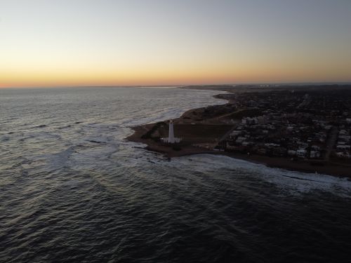 Free Drone shot of the La Paloma lighthouse and ocean coastline during sunset in Uruguay. Stock Photo