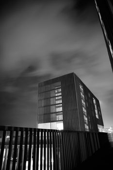 A striking black and white image of a modern building with long exposure sky effects.. striking, black, white