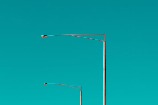 A minimalist photo of street lights against a vibrant turquoise sky in St Kilda, VIC, Australia.