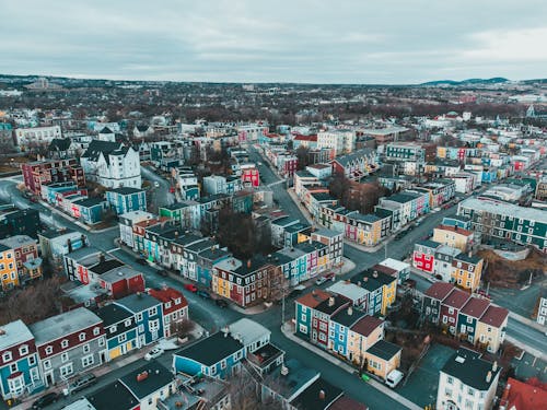 Free Aerial view of town with multicolored residential houses and streets under gloomy cloudy sky Stock Photo