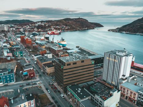 Aerial view of modern cityscape near harbor with ships in serene river valley in overcast weather