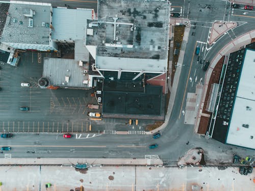 Drone view of contemporary city district with vehicles driving on asphalt road near modern buildings