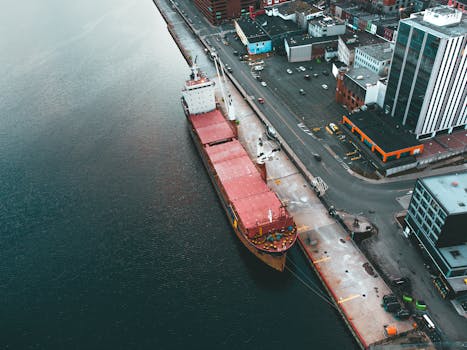 Drone view of modern dock with industrial ship moored in rippling water in daytime