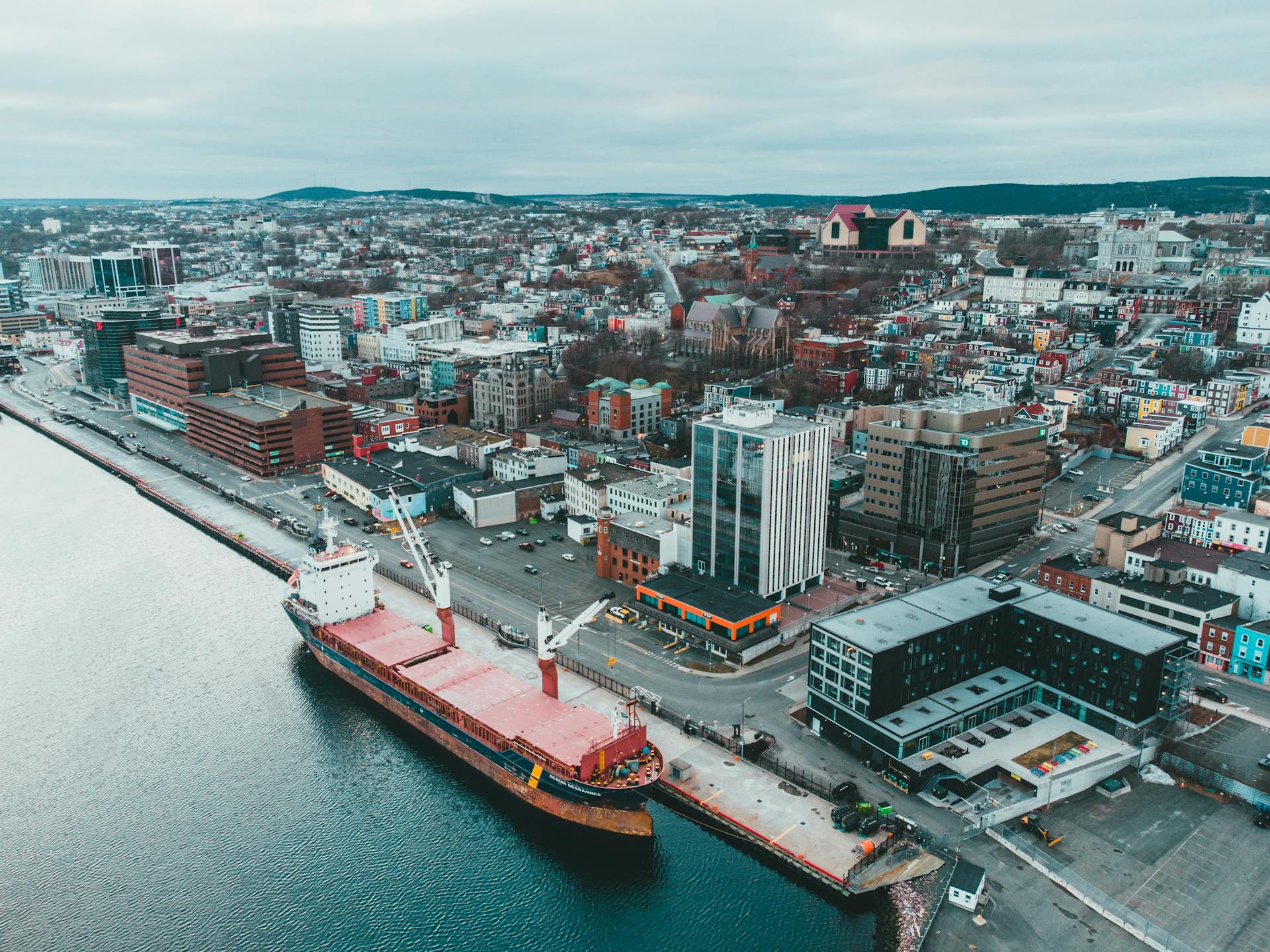 Aerial cityscape showcasing a cargo ship docked at an urban harbor, exemplifying industrial logistics.