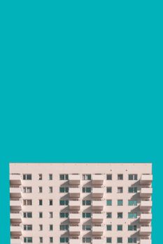 Minimalist photo of a modern apartment building against a striking turquoise sky, with ample copy space.