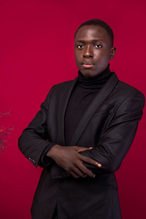 Free Stylish man in a black suit and turtleneck against a vibrant red background. Stock Photo