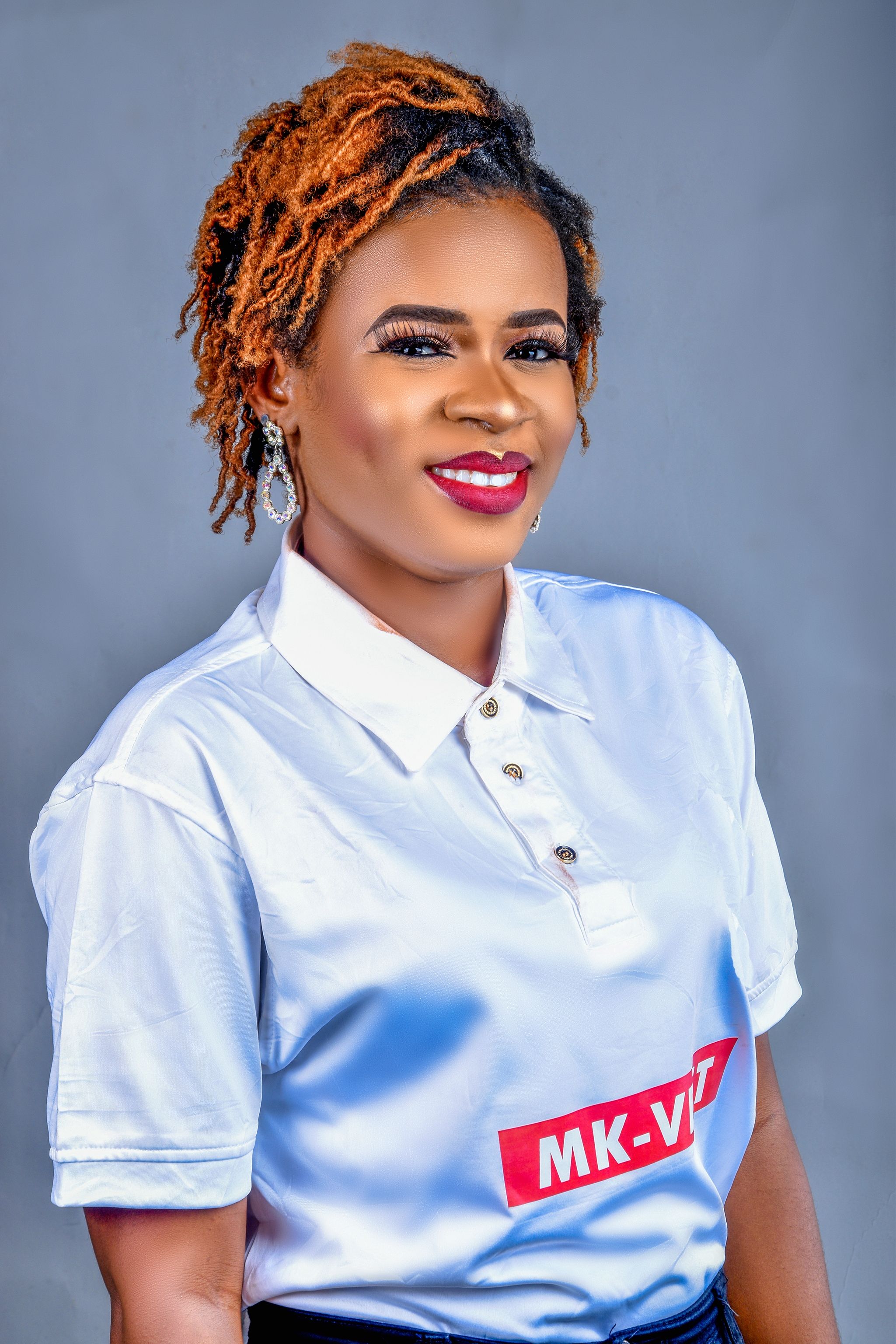 Portrait of a smiling woman with curly hair wearing a white polo shirt.