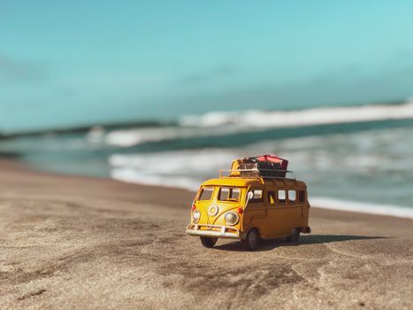 A miniature yellow van on a sunny beach in Cartagena, Colombia, capturing a playful travel vibe.