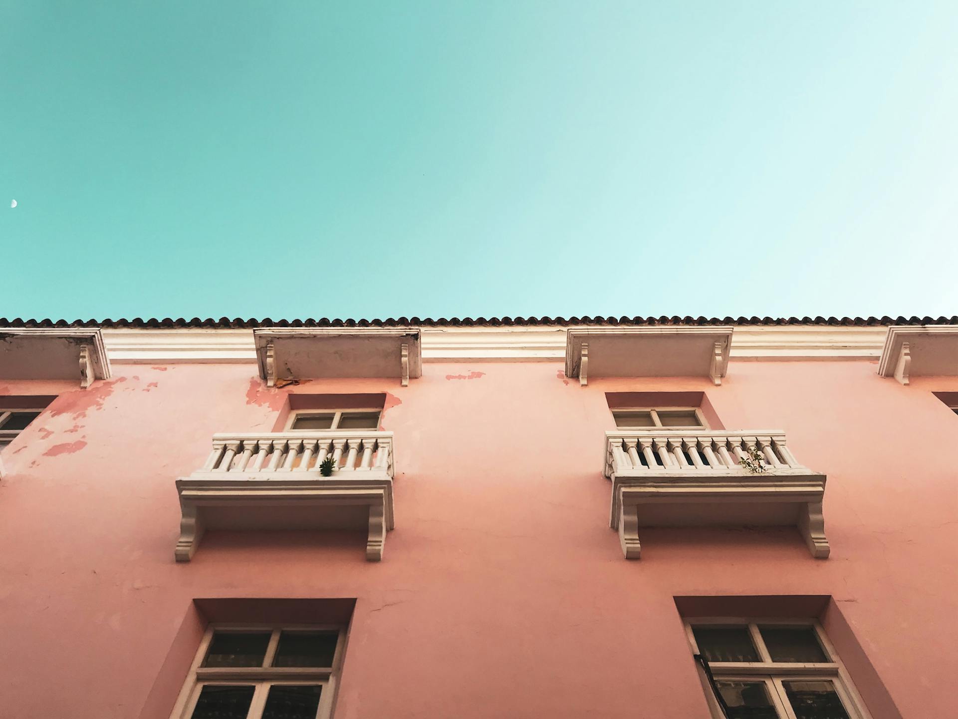 Pink colonial building with balconies in Cartagena against a blue sky.