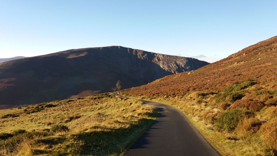 A road winding through the Wicklow Mountains in Ireland on a sunny day