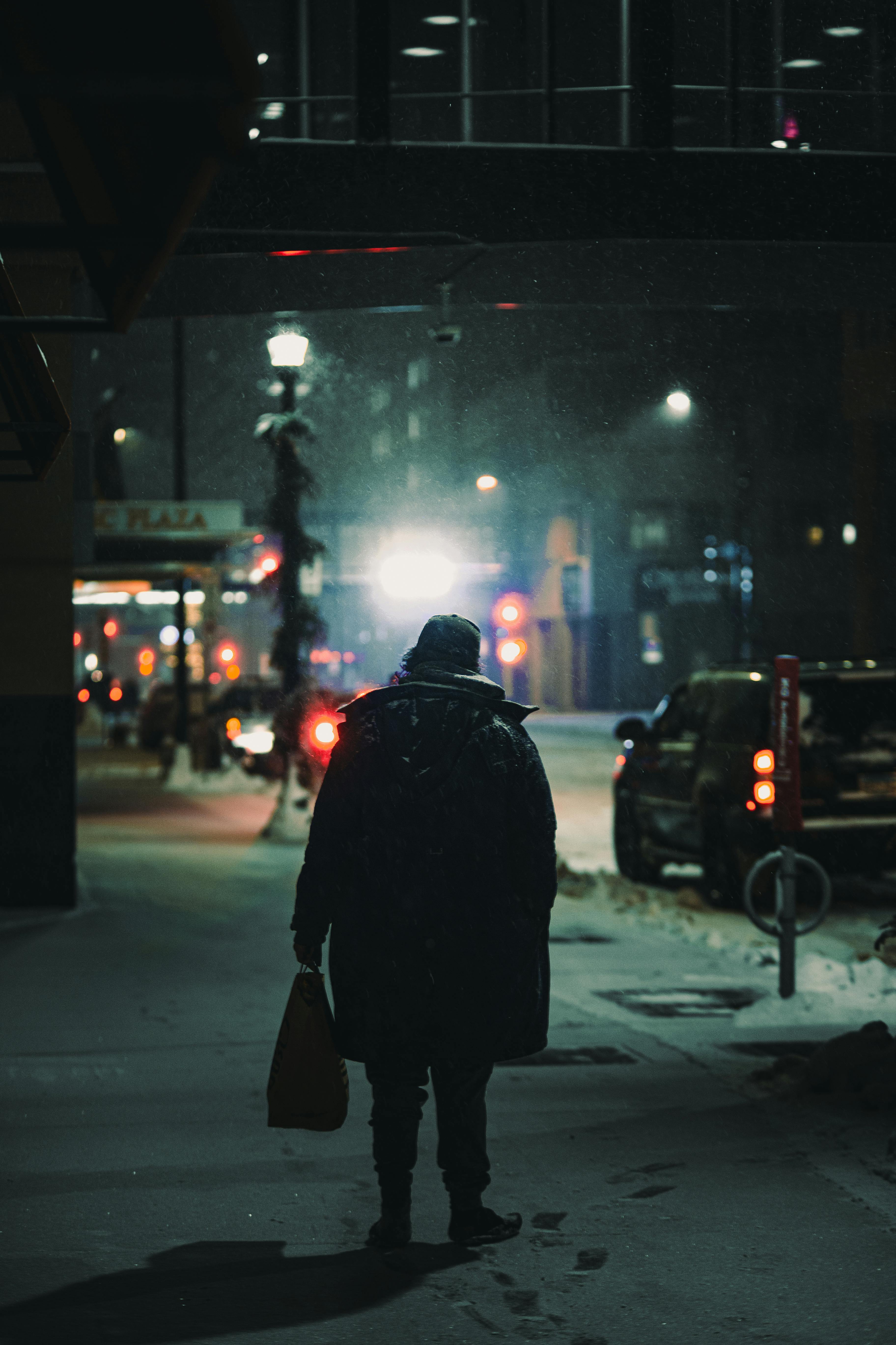 Back view of person walking on a snow-covered street in Minneapolis at night.