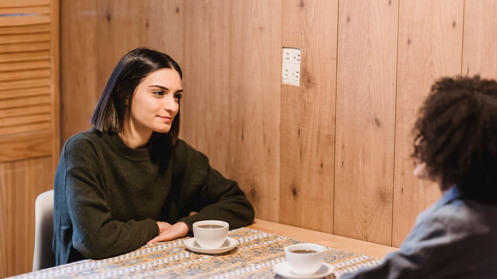 Two adults talking over coffee at a table
