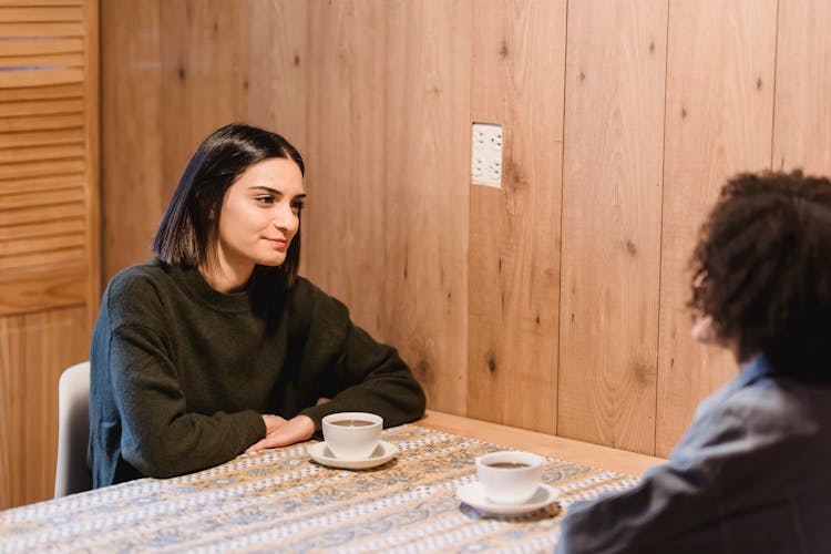 Best Friends Speaking At Table With Cups Of Coffee