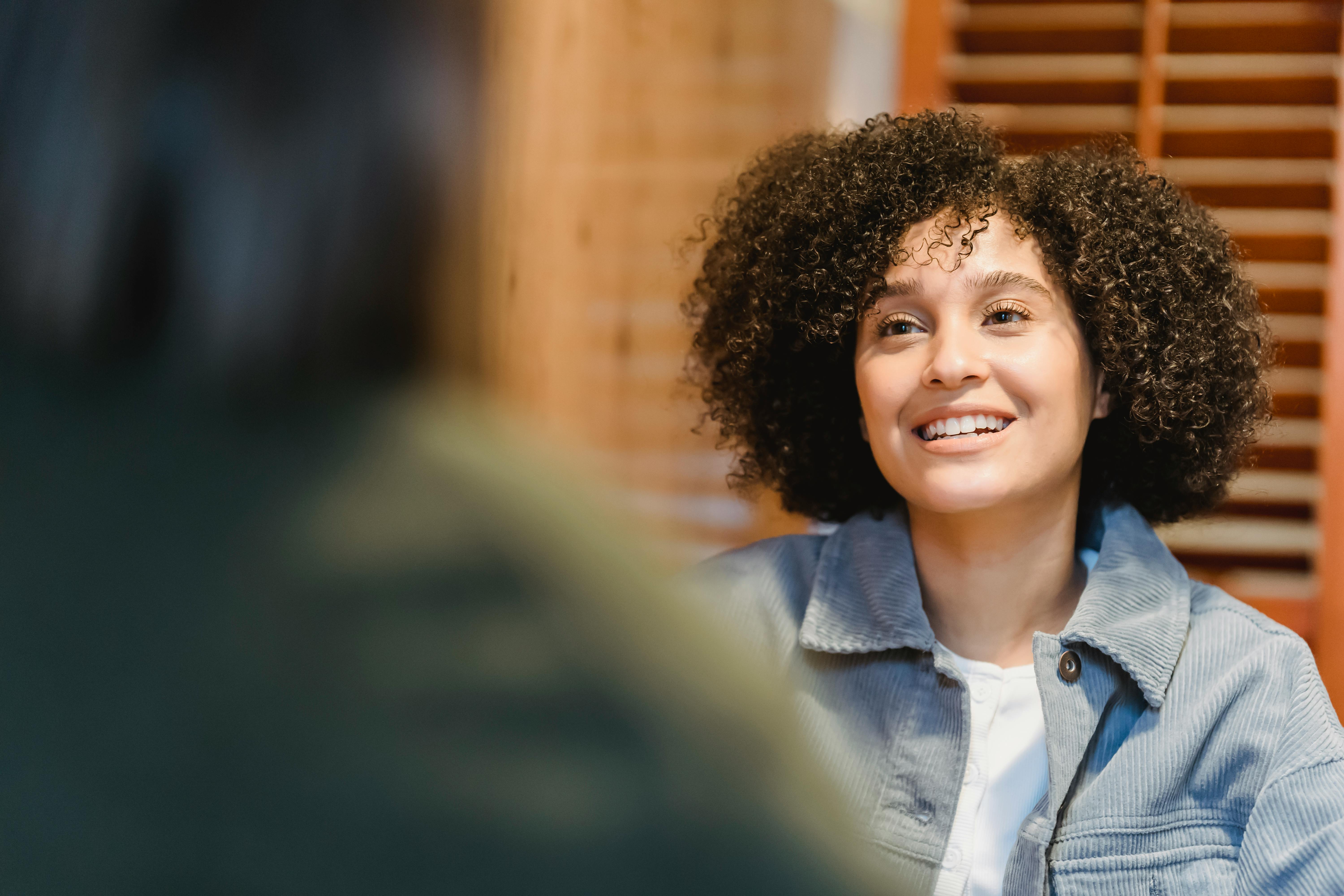 cheerful young woman with afro hairstyle talking with friend