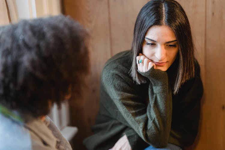 Melancholic Young Woman Communicating With Anonymous Black Best Friend At Home