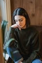 Sad woman in casual wear sitting near window