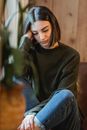 Weary female with closed eyes in casual clothes leaning on hand sitting near window