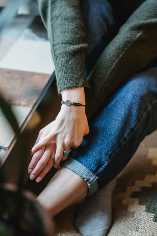 Free From above of crop anonymous female wearing casual clothes and bracelet on wrist and rings sitting near window Stock Photo
